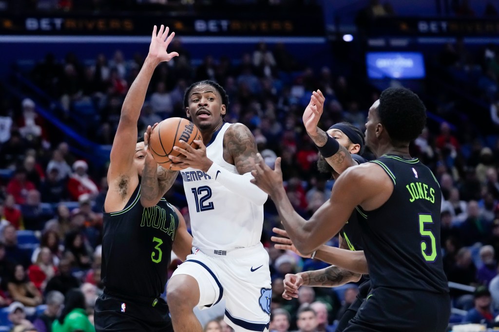 Memphis Grizzlies guard Ja Morant (12) goes to the basket between New Orleans Pelicans guard CJ McCollum (3) and forward Herbert Jones (5).