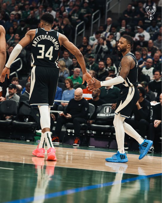 A photo of Giannis Antetokounmpo and Damian Lillard high-fiving on the court.