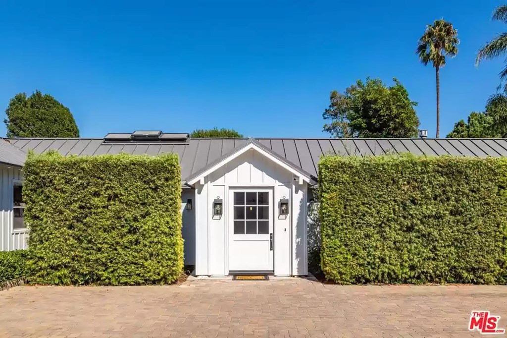 Tall hedges around the large windowed front door add privacy. 