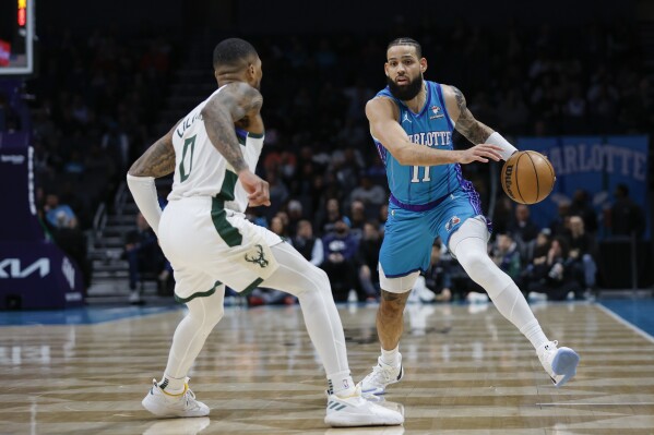 Charlotte Hornets forward Cody Martin, right, drives against Milwaukee Bucks guard Damian Lillard, left, during the first half of an NBA basketball game in Charlotte, N.C., Thursday, Feb. 29, 2024. (AP Photo/Nell Redmond)