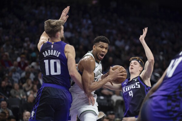 Tiền đạo Giannis Antetokounmpo (34) của Milwaukee Bucks chia tay tiền đạo Domantas Sabonis (10) của Sacramento Kings và người gác đền Kevin Huerter (9) khi anh lái xe lên rổ trong hiệp một của trận đấu bóng rổ NBA ở Sacramento, California, Thứ Ba, ngày 12 tháng 3, 2024. (Ảnh AP/José Luis Villegas)