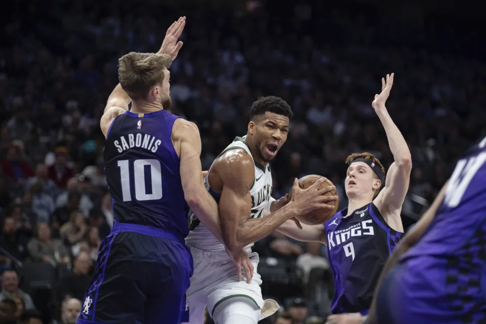 Milwaukee Bucks forward Giannis Antetokounmpo (34) splits Sacramento Kings forward Domantas Sabonis (10) and guard Kevin Huerter (9) as he drives to the basket in the first quarter of an NBA basketball game in Sacramento, Calif., Tuesday, March 12, 2024. (AP Photo/José Luis Villegas)