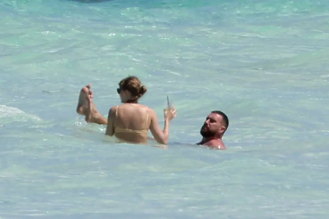 Travis Kelce floats in the clear blue water of the tropical Caribbean.