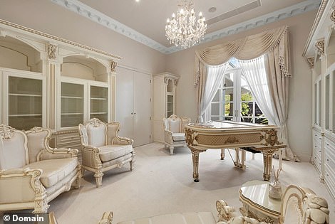 An ultra-luxurious bathroom features two side-by-side claw-foot bathtubs while a separate lounge houses a gold-garnished baby grand piano