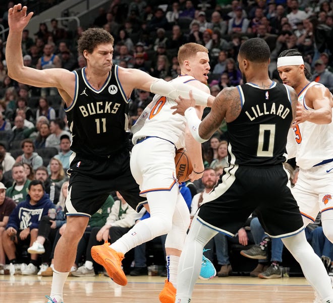 New York Knicks guard Donte DiVincenzo (0) is swarmed by Milwaukee Bucks center Brook Lopez (11) and guard Damian Lillard (0) during the first half of their game Sunday, April 7, 2024 at Fiserv Forum in Milwaukee, Wisconsin.