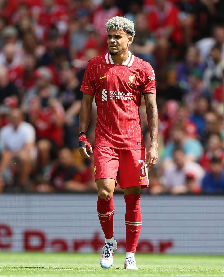 a soccer player wearing a red shirt that says standard chartered on it