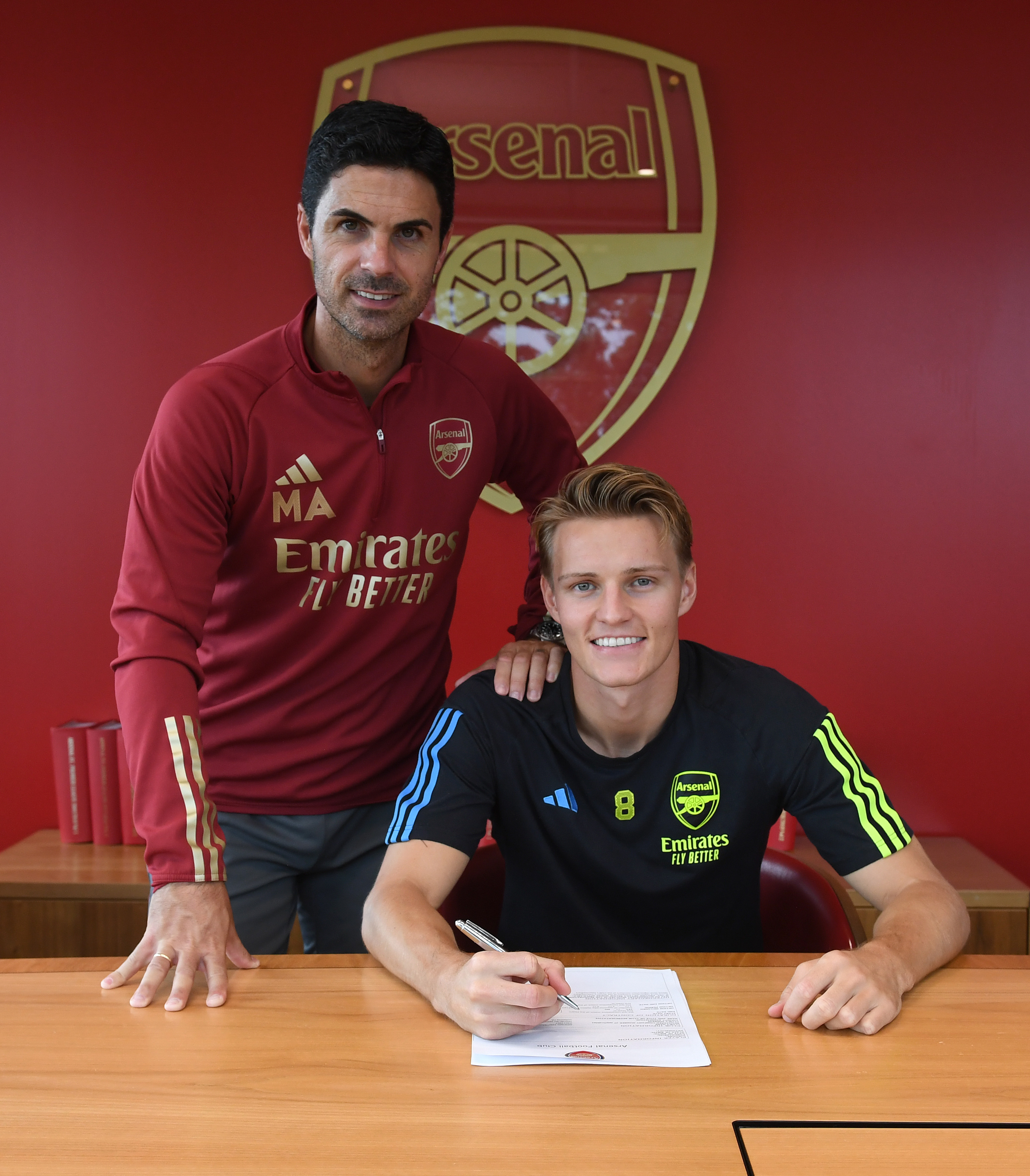 Martin Odegaard signing his new contract, posing for a photo alongside Mikel Arteta.