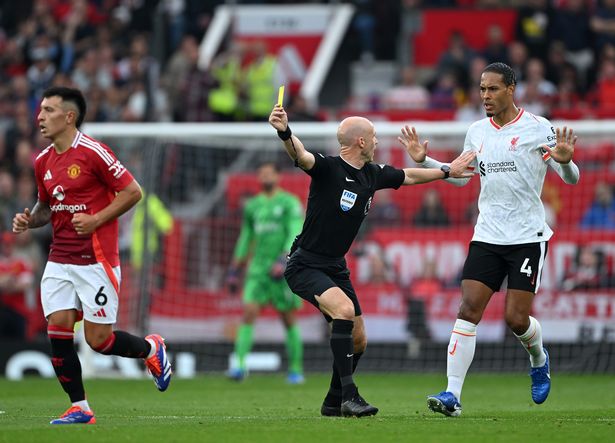 MANCHESTER, ENGLAND - SEPTEMBER 01: Referee Anthony Taylor shows a yellow card to Lisandro Martinez of Manchester United as he holds off Virgil van Dijk during the Premier League match between Manchester United FC and Liverpool FC at Old Trafford on September 01, 2024 in Manchester, England. (Photo by Shaun Botterill/Getty Images)